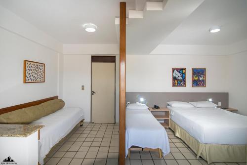 a hotel room with two beds and a mirror at Xênius Hotel in João Pessoa