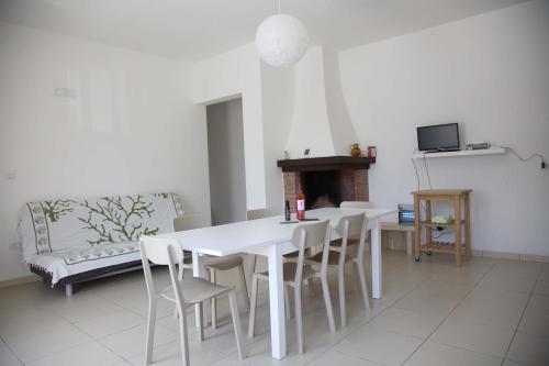 a white dining room with a white table and chairs at Casa Solento in Maruggio