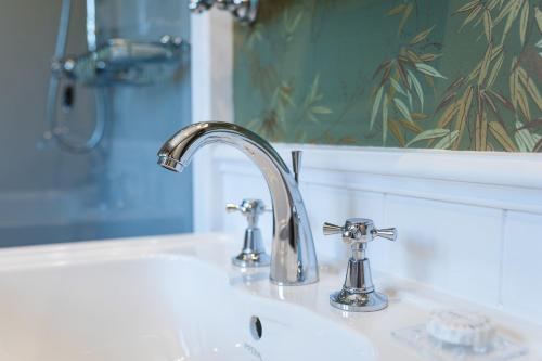 a bathroom sink with a chrome faucet and a mirror at Domaine de Saulon in Saulon-la-Rue
