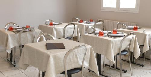 une rangée de tables avec des tables recouvertes de tissus blancs dans l'établissement Contact Hôtel du Cerf, à Château-Gontier