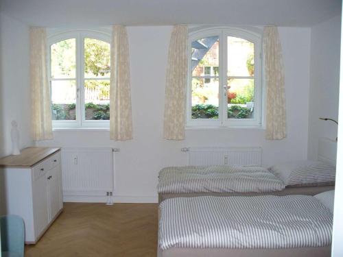 a white room with two beds and two windows at Ferienwohnung Riedner in Lüneburg