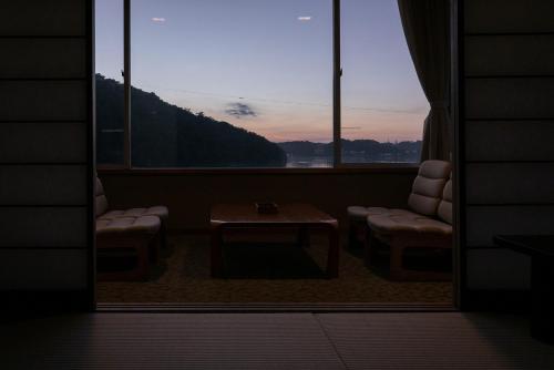 a room with a table and two chairs and a window at Sansuikan Kinryu in Hamamatsu