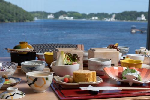 a table with food and cups and a view of the water at Sansuikan Kinryu in Hamamatsu