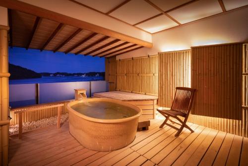 a large bath tub in a room with a chair at Sansuikan Kinryu in Hamamatsu