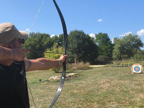 a man holding a bow and arrow in a field at Junior Suite Le Pied de Mulet in Brouchaud