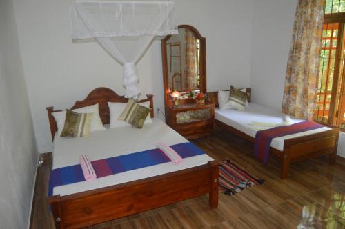 two beds in a room with wooden floors at Sanda Sisila Guest House in Dambulla