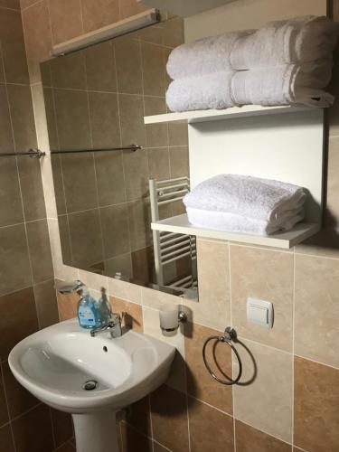 ein Badezimmer mit einem Waschbecken, einem Spiegel und Handtüchern in der Unterkunft Pensiunea Granada in Covasna
