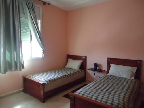 two beds in a small room with a window at Hotel Azul Palace in Sidi Yahia el Gharb
