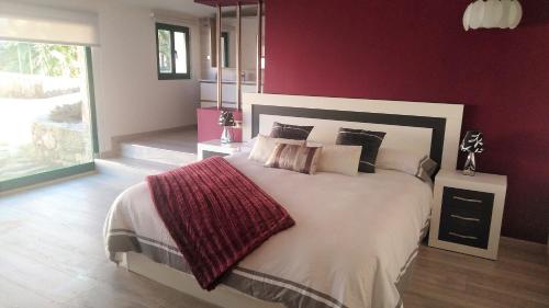 a bedroom with a large bed with a red wall at Casa Spa en montaña in Pontevedra