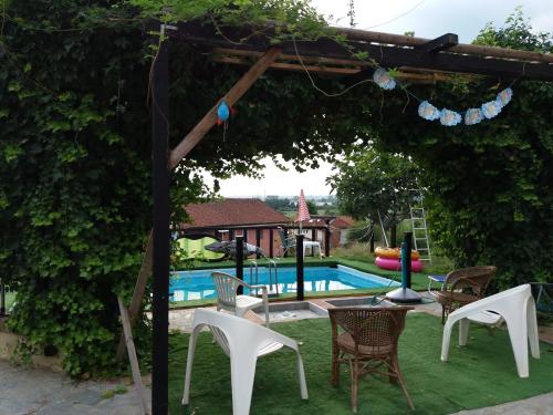 eine Pergola mit Stühlen und ein Pool im Hof in der Unterkunft Casa Tavasso in Asti