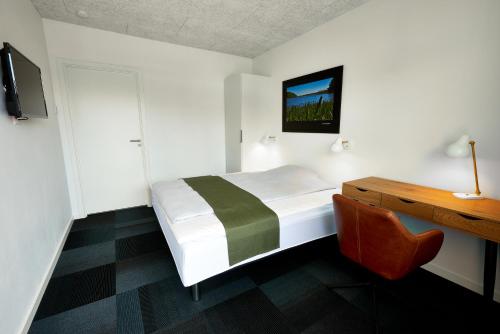 a bedroom with a bed and a desk and a tv at Hotel Phønix in Holstebro