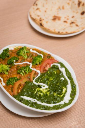 a bowl of food with broccoli and onions on a table at Hotel Orange International in Surat
