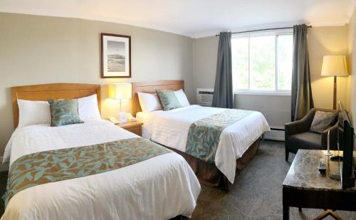 um quarto de hotel com duas camas e uma cadeira em Seasons Inn Halifax em Halifax