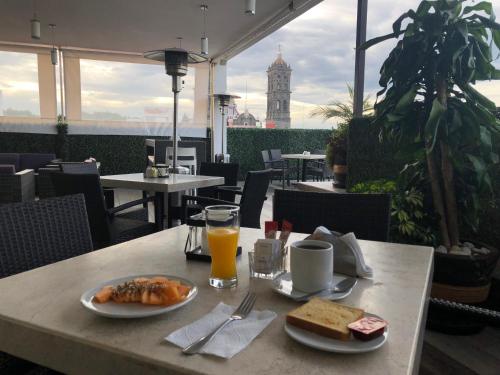a table with a plate of food and orange juice at Hotel Gala in Puebla