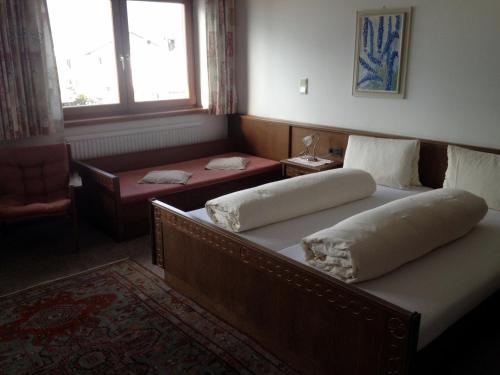 a bedroom with two beds and a table and a window at Pension Wallnöfer in Mieming