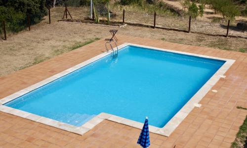 a large blue swimming pool with a brick patio and an umbrella at Mas Del Cigarrer Allotjament Rural in Horta de San Joan
