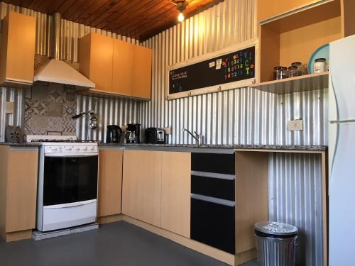 a kitchen with a stove and a sink in it at Berdina casa estilo loft con jardín, parrilla y cochera a 3 cuadras de la plaza de Chacras de Coria in Chacras de Coria