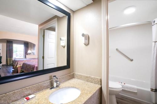 a bathroom with a sink and a mirror and a toilet at Super 8 by Wyndham Murfreesboro in Murfreesboro