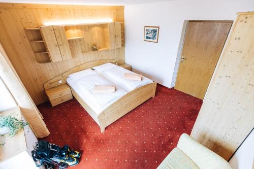a small room with a bed with white sheets at Hotel Schönwies in Trodena