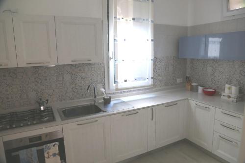 a kitchen with white cabinets and a sink and a window at Via Cipro 16 in Venice-Lido