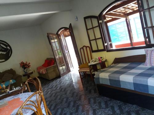 Cette chambre comprend un lit, une table et des fenêtres. dans l'établissement Casa da Olga Itatiaia, à Itatiaia