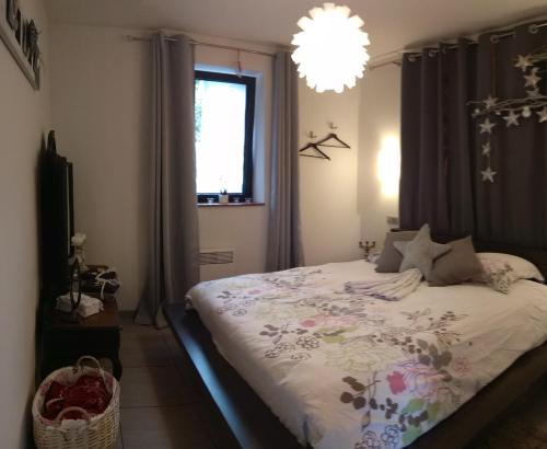 una camera con letto, finestra e lampadario a braccio di Nuits étoilées a Vencimont