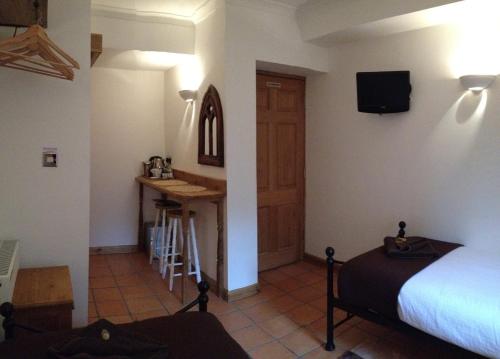 a room with a bed and a table and a kitchen at Tanglewood Gatwick Bed & Breakfast in Crawley