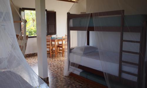 a bedroom with a bunk bed and a dining room at Chalés Nascer do Sol in Diogo