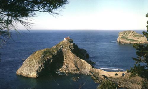 a small island in the ocean with a house on it at Bungalows Portuondo parking gratuito in Mundaka