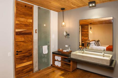 baño con lavabo, cama y espejo en Rodavento Boutique Hotel & Spa, en Valle de Bravo