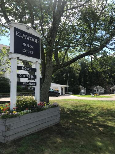 a sign for a hotel with flowers in a yard at Elmwood Motor Court in Old Orchard Beach