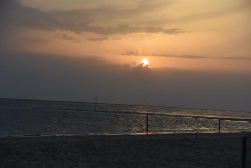 a sunset over the ocean with the sun hiding behind a cloud at Chalet Oester 167 in Ballum