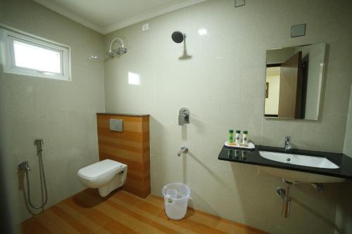 a bathroom with a toilet and a sink and a mirror at Hotel Sree Devi Madurai in Madurai