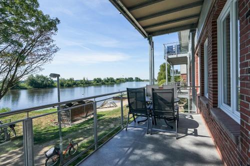 a balcony with chairs and a view of a river at Eiderstrand in Tielen