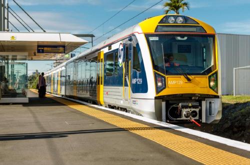 a yellow and white train pulling into a train station at Harbour View Cottage in Auckland