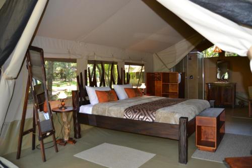 ein Schlafzimmer mit einem Bett in einem Zelt in der Unterkunft Wilderness Seekers Ltd Trading As Mara River Camp in Aitong