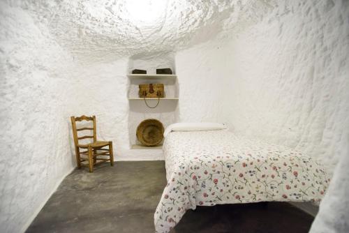 biały pokój z łóżkiem i krzesłem w obiekcie La Cueva de la Abuela w mieście Cenes de la Vega