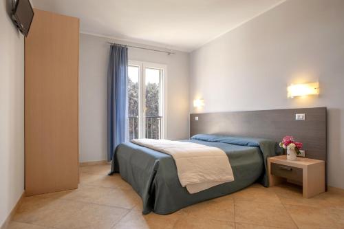 una camera con un grande letto e una finestra di Residence Villa Lo Scoglietto a San Vincenzo