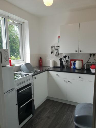 a kitchen with white cabinets and a stove and a window at The Annex Apartment in Weymouth