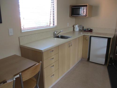 a small kitchen with a sink and a refrigerator at Alhambra Oaks Motor Lodge in Dunedin