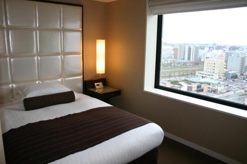 a bedroom with a bed and a large window at Hotel Terrace the Garden Mito in Mito