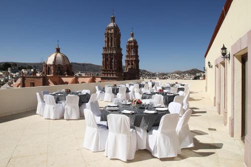 a group of tables and white chairs on a roof at Emporio Zacatecas in Zacatecas