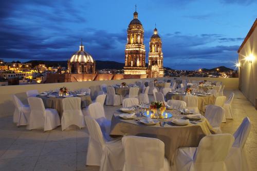 a room with white tables and chairs and a building at Emporio Zacatecas in Zacatecas