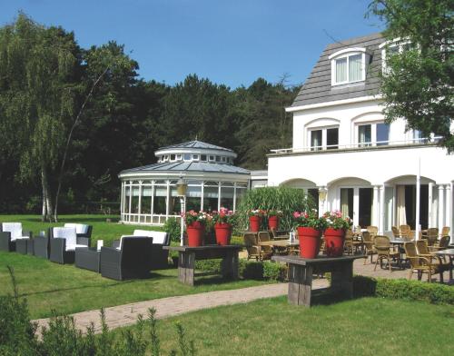 a white house with potted plants and a gazebo at Fletcher Hotel Restaurant De Witte Raaf in Noordwijk