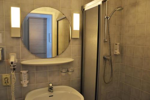 a bathroom with a sink and a mirror and a shower at Fletcher Hotel Restaurant De Witte Raaf in Noordwijk