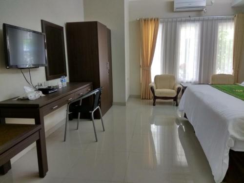 ein Hotelzimmer mit einem Bett, einem Schreibtisch und einem TV in der Unterkunft Puri Ratna Joewita in Batusangkar