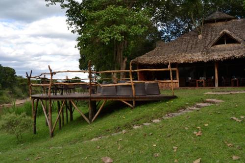 Aitong的住宿－Wilderness Seekers Ltd Trading As Mara River Camp，草屋的建筑,有甲板