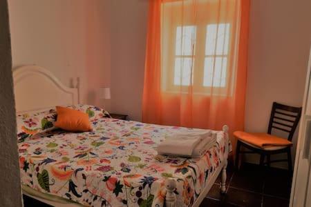 um quarto com uma cama e uma janela com uma cortina laranja em Casa rústica no monte das Oliveiras, Sta Margarida, Tavira em Tavira