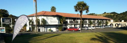 a large building with cars parked in a parking lot at Motel Sierra in Whangarei