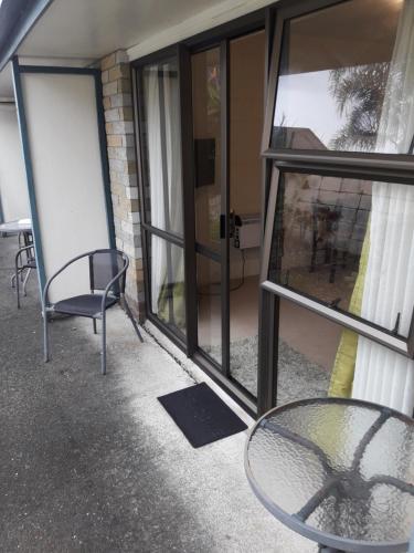 a table and a chair in front of a building at Motel Sierra in Whangarei